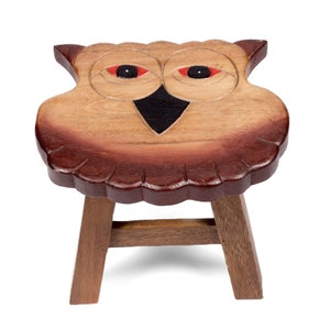 Könnte beinhalten: Ein hölzerner Hocker in Form einer Eule mit brauner und roter Oberfläche. Die Augen der Eule sind rot und der Schnabel ist schwarz. Der Hocker hat drei Beine.