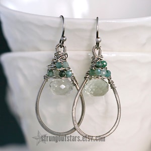 May include: Silver wire wrapped earrings with a teardrop shaped clear quartz crystal and green gemstone beads.