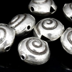May include: A set of silver-toned metal beads with a spiral design. The beads have a hole in the centre for stringing.