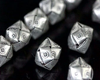 May include: A close-up of ten silver metal beads, each with a unique geometric design. The beads are intricately woven and have a shiny finish.