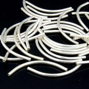 May include: A pile of silver-toned metal bead caps, each shaped like a half-circle. The caps are smooth and shiny, and they are perfect for adding a touch of elegance to jewelry projects.