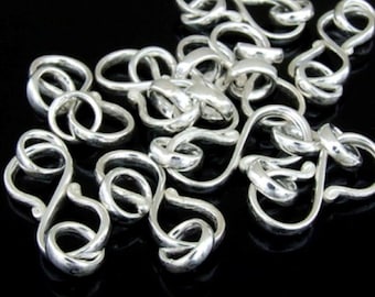 May include: A close-up of a silver chain with a unique, twisted link design. The chain is made of multiple interconnected loops, creating a delicate and intricate pattern.