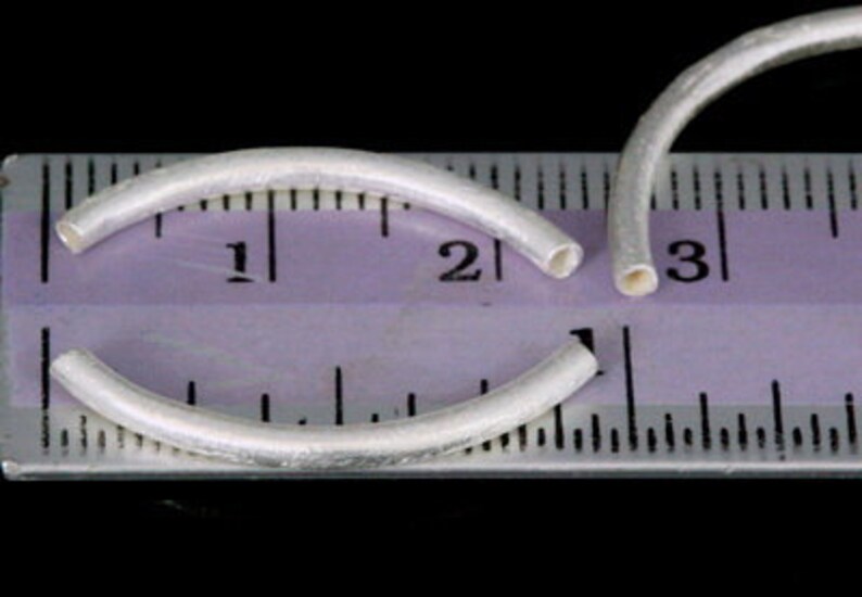 Puede incluir: Dos anillos de salto de plata, cada uno con un di&aacute;metro de aproximadamente 2,5 cm, se colocan sobre una regla. La regla muestra que los anillos son ligeramente m&aacute;s grandes que 2,5 cm.