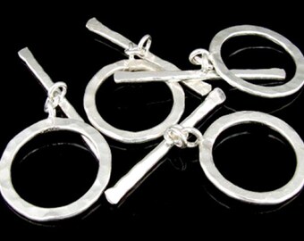 Può includere: Cinque chiusure a scatto in argento con finitura martellata. Ogni chiusura ha un anello rotondo e una barra dritta che scorre attraverso l'anello.