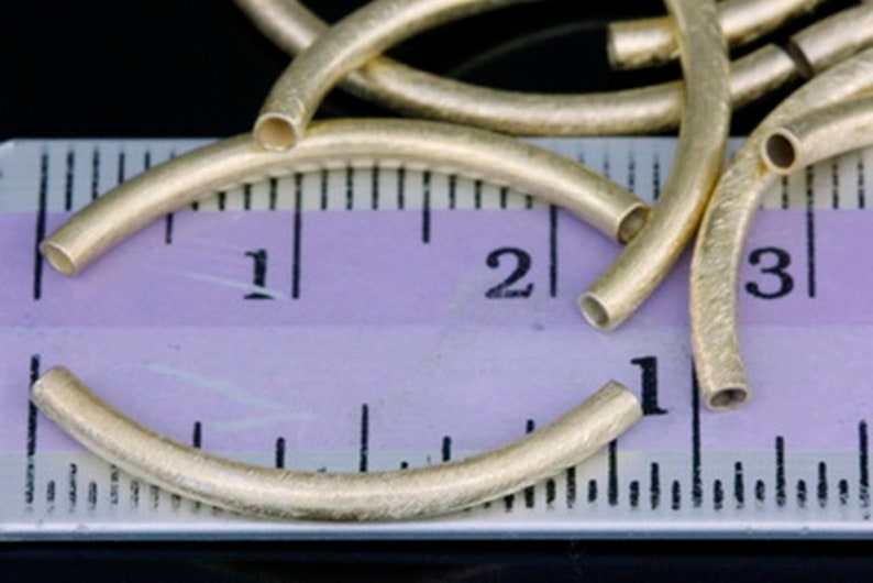 Puede incluir: Primer plano de aros de metal de color dorado, que miden aproximadamente 2,5 cm de di&aacute;metro, con una superficie ligeramente texturizada. Los aros est&aacute;n dispuestos sobre una regla con marcas en cent&iacute;metros.