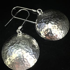 May include: A pair of silver hammered disc earrings with a simple hook closure.