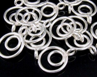 May include: A group of silver-toned metal jewellery findings with a circular design. Each finding has two concentric circles, with a smaller circle inside a larger circle. The findings have a loop at the top for attaching to jewellery.