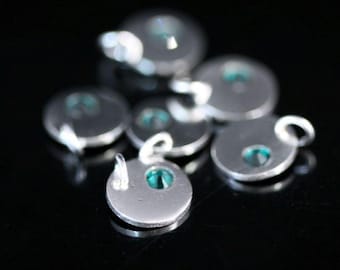 Pode incluir: Um grupo de pingentes de prata com pequenas pedras redondas de cor turquesa. Cada pingente tem um laço para prender a um colar ou pulseira.