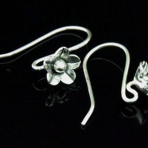 May include: A pair of silver flower-shaped earring hooks. The hooks are made of sterling silver and have a delicate floral design.