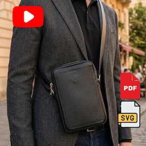 May include: A black leather crossbody bag with a textured surface and a zipper closure, worn over a dark gray blazer and a black polo shirt. The bag features a slim, rectangular shape with a single adjustable shoulder strap and metal hardware.