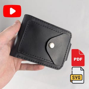 May include: A black leather bifold wallet featuring a rectangular front pocket with a triangular flap secured by a silver metal snap button. The wallet is constructed with visible black stitching along the edges of the pocket and the main body.