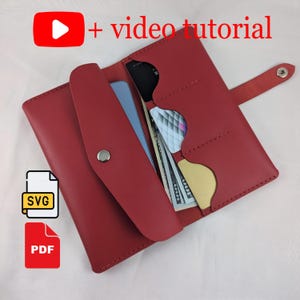 Puede incluir: Una cartera de cuero roja con múltiples compartimentos, incluyendo ranuras para tarjetas, efectivo y un teléfono. La cartera está abierta, revelando su contenido. La imagen incluye el texto "+ video tutorial" e iconos para archivos SVG y PDF.