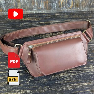 Può includere: Un marsupio in pelle marrone con uno scomparto principale rettangolare dotato di chiusura a zip orizzontale, una tracolla regolabile abbinata e finiture in metallo. La borsa presenta una finitura liscia e un design strutturato con cuciture a vista.