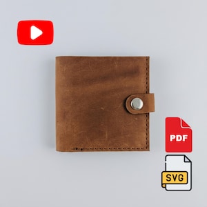May include: A square brown leather wallet featuring visible stitching along the edges and a small tab closure secured with a silver-colored metal snap button. The surface of the leather displays a natural, textured finish with subtle variations in tone.