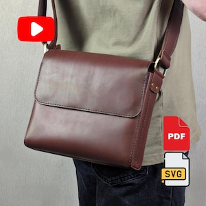 Puede incluir: Un bolso bandolera de cuero marrón oscuro con solapa rectangular, costuras visibles en los bordes y una correa ajustable a juego. El bolso cuenta con herrajes metálicos y un acabado liso, presentado con iconos de YouTube, PDF y SVG.