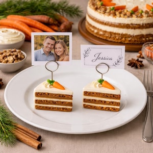 Puede incluir: Dos portatarjetas con forma de porción de pastel de zanahoria con una zanahoria en miniatura encima se encuentran en un plato blanco. Se muestra una foto y una tarjeta con el nombre "Jessica". Un pastel de zanahoria entero está en el fondo.