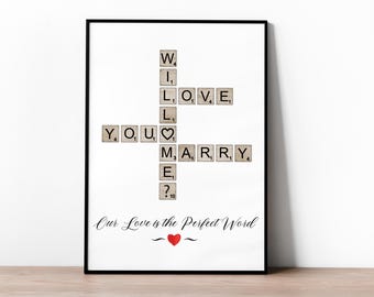Puede incluir: Una impresión enmarcada en blanco con las palabras "Will You Marry Me?" deletreadas con fichas de Scrabble. Las fichas están dispuestas en formato de crucigrama. El texto "Our Love is the Perfect Word" está escrito debajo del crucigrama.