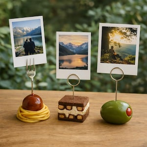 Könnte beinhalten: Drei einzigartige Fotohalter mit Landschaftsbildern. Einer zeigt eine Fleischkugel auf Spaghetti mit einer Gabel, ein weiterer ein quadratisches Dessert und der letzte eine grüne Olive. Alle haben goldfarbene Drahtbügel.