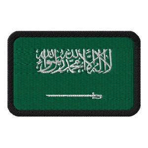 Puede incluir: Un parche verde bordado con una inscripción árabe blanca y una espada blanca. El parche tiene un borde negro.