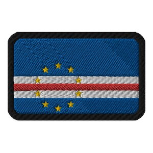 May include: A blue and white embroidered patch with a red stripe and five yellow stars. The patch is surrounded by a black border.