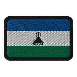Könnte beinhalten: Ein rechteckiger gestickter Aufnäher mit der Flagge von Lesotho. Die Flagge zeigt drei horizontale Streifen in Blau, Weiß und Grün, mit einem schwarzen, weißen und roten Symbol in der Mitte.