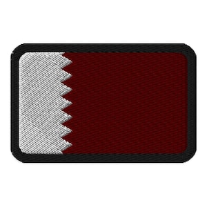 Puede incluir: Un parche bordado blanco y granate con un borde negro. El parche presenta la bandera de Qatar.