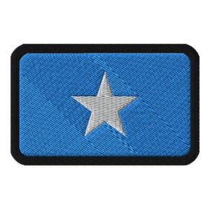 May include: A blue fabric patch with a white five-pointed star in the center. The patch has a black border.