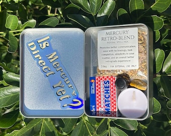May include: A silver metal tin containing a Mercury Retro-Blend herbal spell mix, a box of 32 wooden matches, a small dark glass vial, a white tea light candle, and a yellow stone. The lid features the text Is Mercury direct yet?