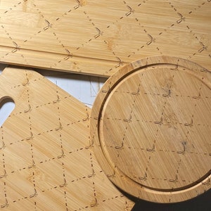Könnte beinhalten: Drei Schneidebretter aus Holz mit einem Rautenmuster. Das größte Brett ist rechteckig, das mittlere Brett ist quadratisch und das kleinste Brett ist rund.