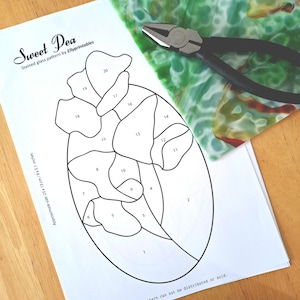 Könnte beinhalten: Ein Glasmalerei-Muster namens "Sweet Pea" mit nummerierten Abschnitten, ca. 23 x 13 cm. Eine grüne und weiße Glasscheibe und eine Zange mit schwarzem Griff sind ebenfalls sichtbar. Das Muster ist von Ellyprintables.