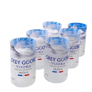 Puede incluir: Seis vasos de chupito de vidrio transparente con un diseño marmoleado azul y blanco. Cada vaso presenta el logotipo de Grey Goose Vodka y el texto: "Grey Goose Vodka", "Destilado y embotellado en Francia", y "40% vol".