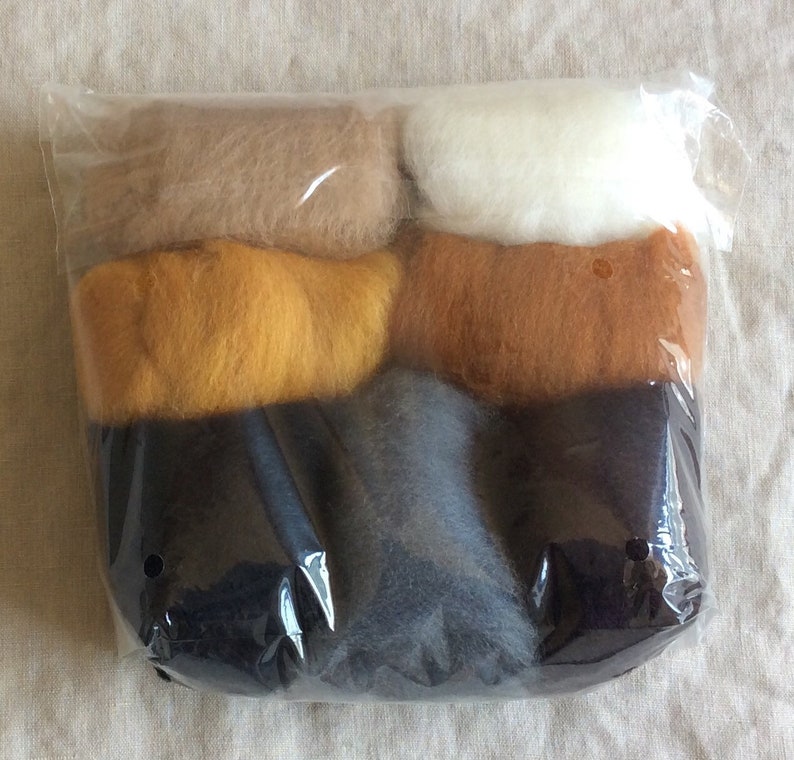 May include: A package of five different colors of wool roving. The colors are beige, yellow, brown, dark gray, and white.