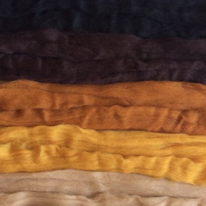 May include: A stack of different colored wool roving, including white, beige, yellow, orange, brown, black, and gray.