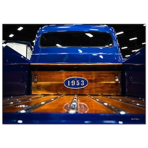 Könnte beinhalten: Die Rückseite eines blauen Ford Pickup Trucks aus dem Jahr 1953 mit einer Holzladefläche und einem blauen ovalen Emblem mit der Jahreszahl 1953 in Weiß.
