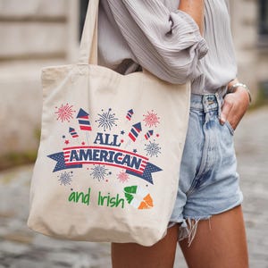 Könnte beinhalten: Beigefarbene Tragetasche mit dem Text "ALL AMERICAN and Irish" in Rot, Weiß, Blau und Grün. Das Design zeigt Feuerwerk und die irische Flagge. Die Tasche wird über der Schulter getragen.