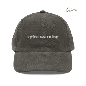 May include: Olive green corduroy baseball cap with the text "spice warning" embroidered in white.