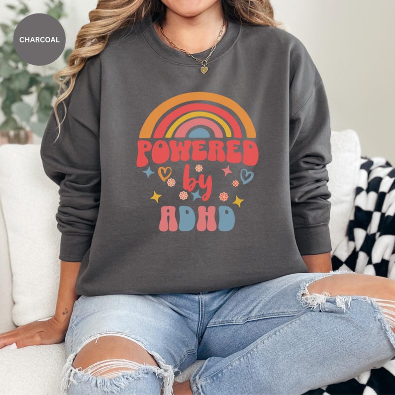 Woman wears Charcoal sweatshirt with slogan Powered By ADHD