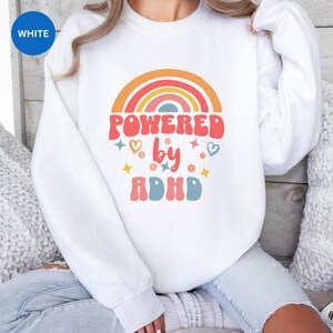 Woman wears White sweatshirt with slogan Powered By ADHD