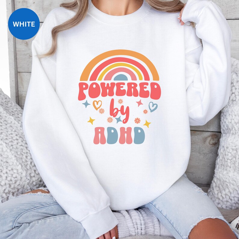 Woman wears White sweatshirt with slogan Powered By ADHD