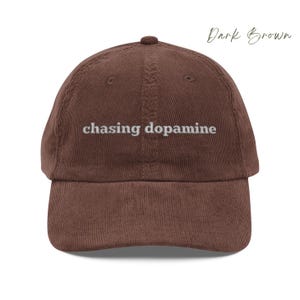 Vintage Corduroy dad hat in dark brown with embroidered text “chasing dopamine” in light grey thread . A minimalist, mental health inspired design.