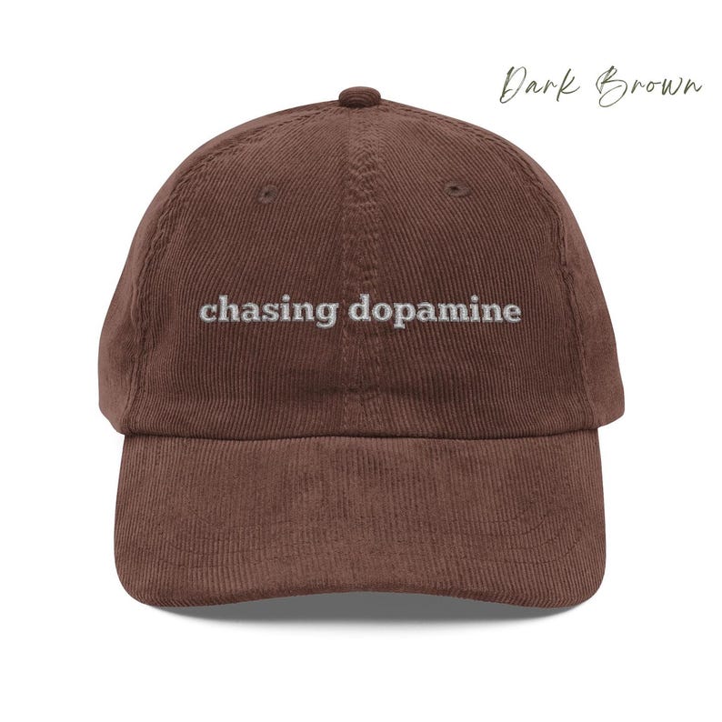 Vintage Corduroy dad hat in dark brown with embroidered text “chasing dopamine” in light grey thread . A minimalist, mental health inspired design.