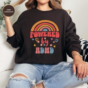 Woman wears Dark Chocolate sweatshirt with slogan Powered By ADHD