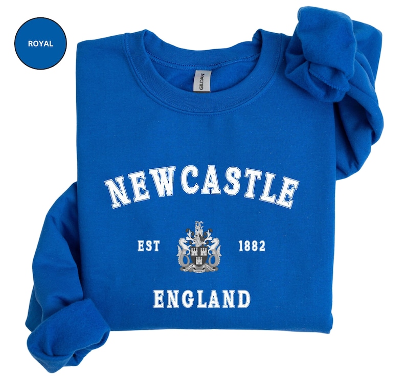 Lay flat royal blue sweatshirt with Newcastle  England, EST 1882 and the Newcastle coat of arms in White distressed text. Also in Black, Dark Heather, Forest Green, Navy, Sand, Sport Grey and White. Sizes from Small to XXL.