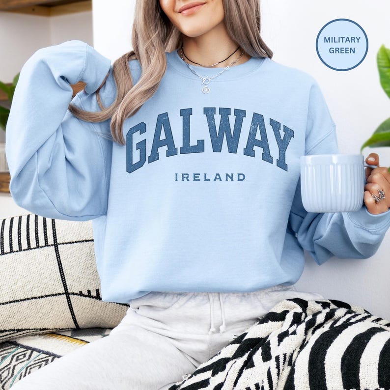 Woman wears light blue sweatshirt with Galway, Ireland in a darker blue vintage style text. Option to customise.