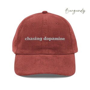 Vintage Corduroy dad hat in burgundy with embroidered text “chasing dopamine” in light grey thread . A minimalist, mental health inspired design.