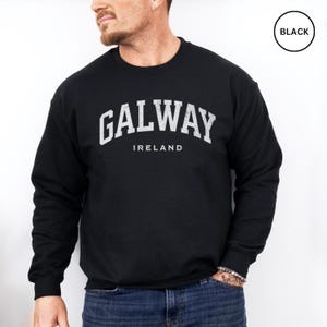 Man wears black sweatshirt with Galway, Ireland in a white vintage style text. Option to customise.