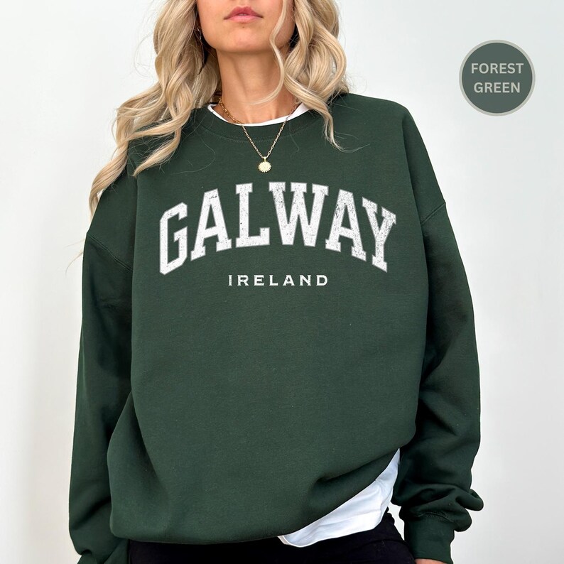 Woman wears forest green sweatshirt with Galway, Ireland in a marine vintage style text. Option to customise.