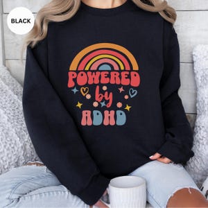 Woman wears Black sweatshirt with slogan Powered By ADHD