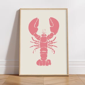 Peut inclure: Une impression de silhouette de homard rose dans un cadre en bois. Le homard est face à l'avant, les pinces levées.