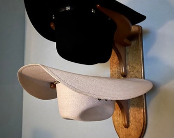 Wooden hat rack with two curved and slightly angled support forks.  Rack accepts hats with brim sizes up to 4-1/2 inches.